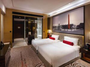 Sofitel Guangzhou Sunrich في قوانغتشو: غرفة فندق بسريرين ومخدات حمراء