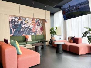 um lobby com dois sofás e duas mesas e um mural em ibis Martigues Centre em Martigues