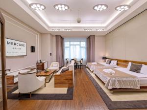 una camera d'albergo con due letti e un salone di Mercure Bydgoszcz Sepia a Bydgoszcz