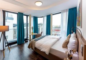 a bedroom with a bed with blue curtains and a balcony at KONCEPT HOTEL Benedikt vormals H2O in Siegburg