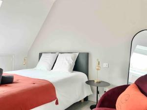 1 dormitorio con 1 cama blanca grande y 1 silla en La villa des Dunes - 80m de la plage/paddle/vélos, en Fouesnant