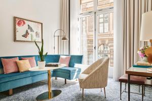 a living room with a blue couch and a table at Hôtel du Louvre, in The Unbound Collection by Hyatt in Paris
