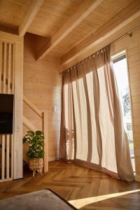 トシェンサチにあるWood House Trzęsaczのカーテン付きの大きな窓が備わる客室です。