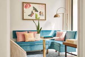- un salon avec un canapé bleu et des oreillers roses dans l'établissement Hôtel du Louvre, in The Unbound Collection by Hyatt, à Paris