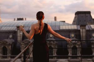 a woman in a black dress looking at a building at Hôtel du Louvre, in The Unbound Collection by Hyatt in Paris