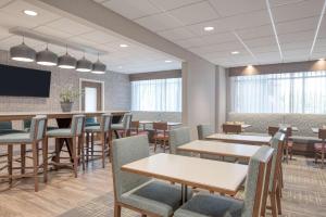 a dining room with tables and chairs and a flat screen tv at Hampton Inn Cleveland-Airport/Tiedeman Road in Brooklyn