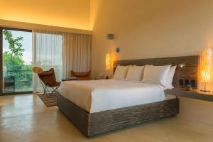 a hotel room with a large bed and a balcony at Andaz Mayakoba - a concept by Hyatt in Playa del Carmen
