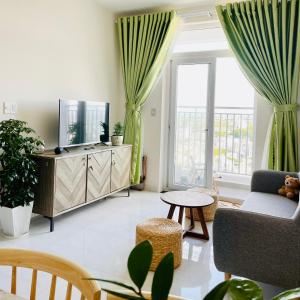 een woonkamer met een tv, een bank en een raam bij Mayhome Phan Rang - 2BR City view - 3km to beach in Kinh Dinh