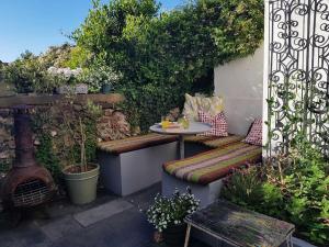 eine Terrasse mit einem Tisch und Bänken in einem Garten in der Unterkunft Stylish townhouse 15 mins to Laines & Seafront in Brighton & Hove