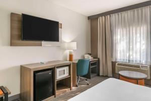 a hotel room with a bed and a desk with a tv at Comfort Inn & Suites Louisville Airport Fair & Expo in Louisville