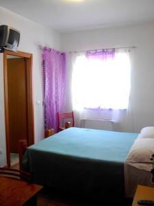 ヴィッラピアーナにあるHotel Celestinaのベッドルーム1室(ベッド1台付)、紫色のカーテン付きの窓が備わります。