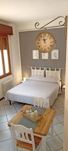 a bedroom with a bed with a table and a clock on the wall at Cecily's House in Mantova