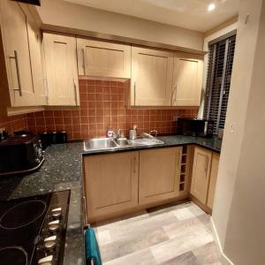 una cocina con armarios de madera y fregadero. en Crossways Cottage Quirky 2 bedroom cottage in Central location, en Peebles