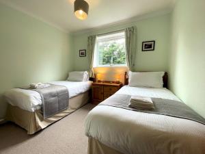 due letti in una stanza con finestra di Pass the Keys Traditional Scottish Cottage in Beautiful Location a Rockcliffe