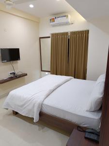 um quarto com uma cama branca e uma televisão em RK COMFORTS em Bangalore