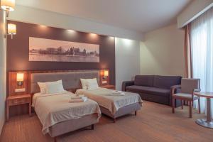 ein Hotelzimmer mit 2 Betten und einem Sofa in der Unterkunft Hotel Centrum Malbork in Malbork