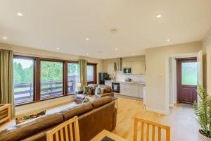 a living room with a couch and a kitchen at Conifer Lodge 25 with Hot Tub in Newton Stewart