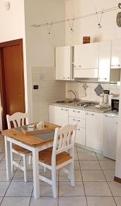 Una cocina con una mesa de madera y gabinetes blancos. en Cecily's House, en Mantua