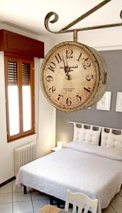 un grande orologio appeso sopra un letto in una stanza di Cecily's House a Mantova