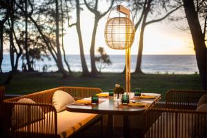 a table with a lamp and chairs with the ocean at Le Méridien Phuket Mai Khao Beach Resort in Mai Khao Beach