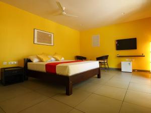 a bedroom with a bed with yellow walls and a flat screen tv at Island Private Beach Retreat - Gokarna in Haldipur