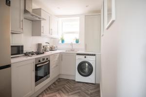 a kitchen with white cabinets and a washer and dryer at Harbour Heights in Folkestone