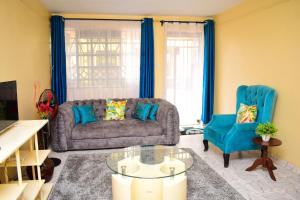 a living room with a couch and two blue chairs at Rozie Apartment in Kisumu