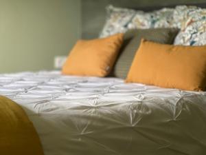 a white bed with orange pillows on top of it at Gîtes de charme "l'écrin de Vendée" jacuzzi privatif, piscine chauffée, prestations bien être, vélos à 10 mn de l'océan sur 3,5 h de verdure in Sallertaine +98 photos
