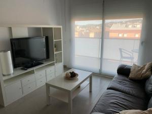 sala de estar con sofá, TV y mesa en Apartamento con piscina Cerca de la playa, en Sant Antoni de Calonge