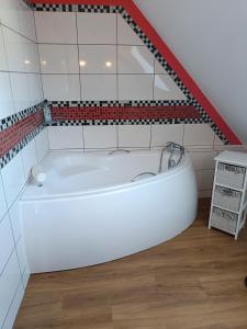 a white bath tub in a bathroom with red and white tiles at Farcik Apartament in Nowa Wieś