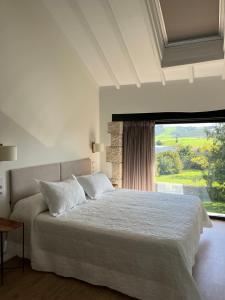 Un dormitorio con una cama grande y una ventana grande. en La Casona de Suesa, en Suesa