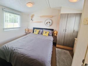 a bedroom with a bed with two yellow pillows at Lakeside Cotswold Holiday Home in Cirencester
