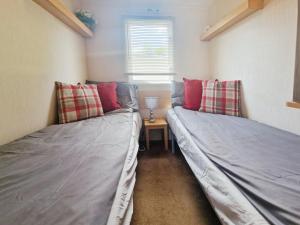 two twin beds in a room with a table at Lakeside Cotswold Holiday Home in Cirencester