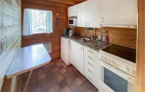 cocina con armarios blancos, fregadero y fogones en Stuga 4, en Nybro