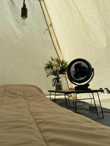 - un ventilateur assis sur une table à côté d'un lit dans l'établissement Moon hill camp, à Kampong Egang