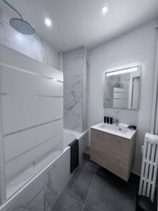 ein weißes Badezimmer mit einem Waschbecken und einer Badewanne in der Unterkunft 4P - 1BR - Boulogne Paris Parc des Princes in Boulogne-Billancourt