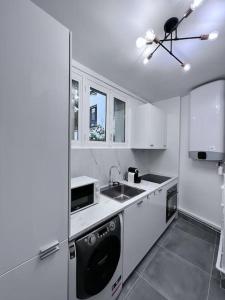 eine weiße Küche mit einer Spüle und einem Geschirrspüler in der Unterkunft 4P - 1BR - Boulogne Paris Parc des Princes in Boulogne-Billancourt