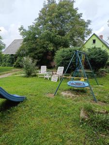 a swing set in a yard with two chairs at Farcik Apartament in Nowa Wieś