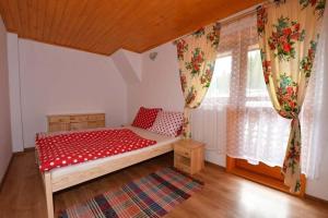 a bedroom with a bed with red sheets and a window at Chata Erika in Pusté Pole