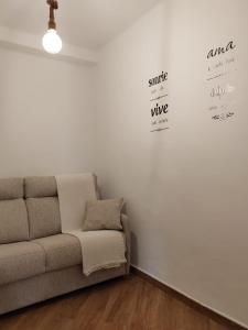 sala de estar con sofá y pared blanca en Loreto 6, en Albacete