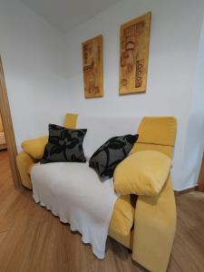 1 dormitorio con cama y sofá amarillo en Loreto 6, en Albacete