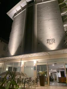 a building with tables and chairs in front of it at Hotel Audi Frontemare in Rimini