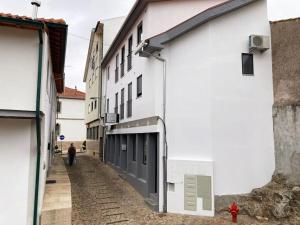 eine Person, die eine Straße neben einem weißen Gebäude entlanggeht in der Unterkunft Casa do Largo in Bragança