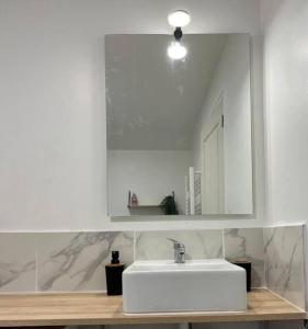 een badkamer met een witte wastafel en een spiegel bij Petite maisonnette proche de Giverny in Bonnières-sur-Seine