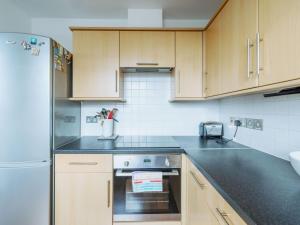 a kitchen with wooden cabinets and a stove top oven at Pass the Keys Central Location Flat near Old St and Dalston Overlooking Rosemary Park and Regents Canal in London