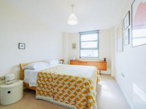a bedroom with a bed with a yellow and white blanket at Pass the Keys Central Location Flat near Old St and Dalston Overlooking Rosemary Park and Regents Canal in London