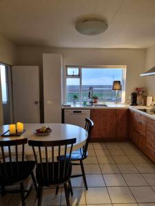 a kitchen with a table and chairs and a view of the ocean at Selið Farm Stay - Guesthouse 