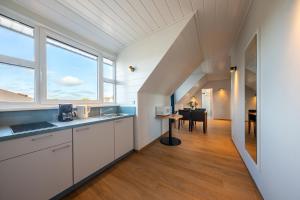 una cocina con armarios blancos y una mesa en una habitación en Residenz Südwesthörn, en Norderney