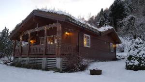 una cabaña de madera en la nieve con luces de Navidad en Cosy chalet, 100m2 with fjordview!, en Lauvstad