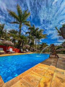 una piscina en un complejo con palmeras en Pousada Villa 3 Lagos en Santo Antônio do Pinhal